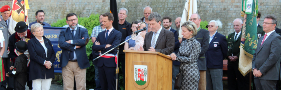 Das Bild zeigt Bürgermeister Gabor Huszar aus Szentgotthárd mit seiner Dolmetscherin bei seinem Grußworten. Bürgermeister Günter steht dabei hinter den beiden Ehrengästen. James Chèron aus Monterau (links) und Dr. Achim Brötel (am rechten Bildrand) sind aufmerksame Zuhörer.