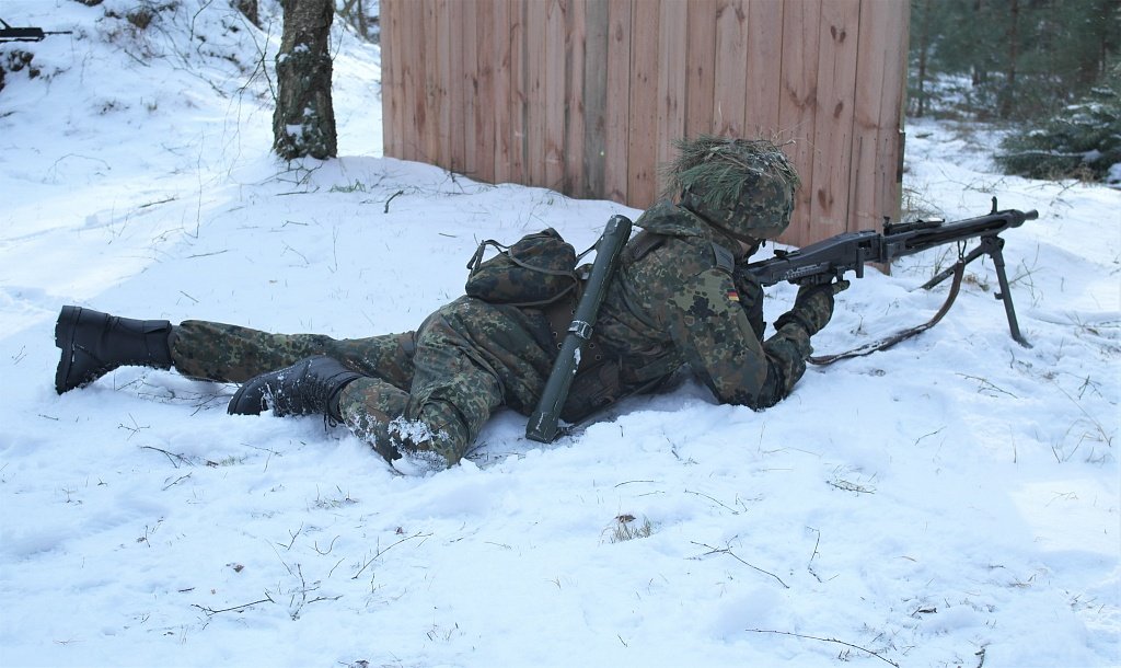im Schnee liegener Reservist mit MG im Anschlag