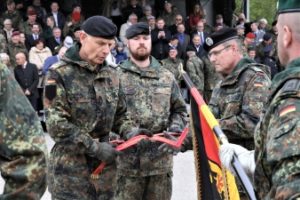  Der Stellvertreter des Inspekteurs der Streitkräftebasis, Generalleutnant Jürgen Weigt, verleiht dem frisch umbenannten Heimatschutzregiment 1 das passende Fahnenband. (Foto: Bundeswehr/Sauer)